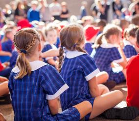School children sitting down with their backs facing the camera